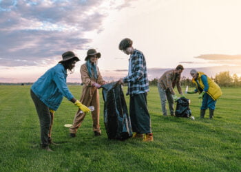 Volunteers collecting trash on green grass field