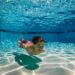 Shirtless kid swimming under water
